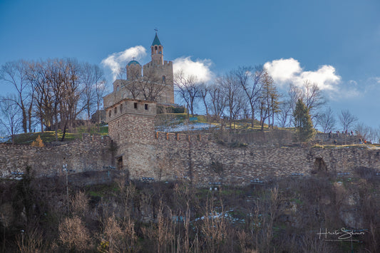 Tsarevets Fortress on a hill with a cloudy sky in the background